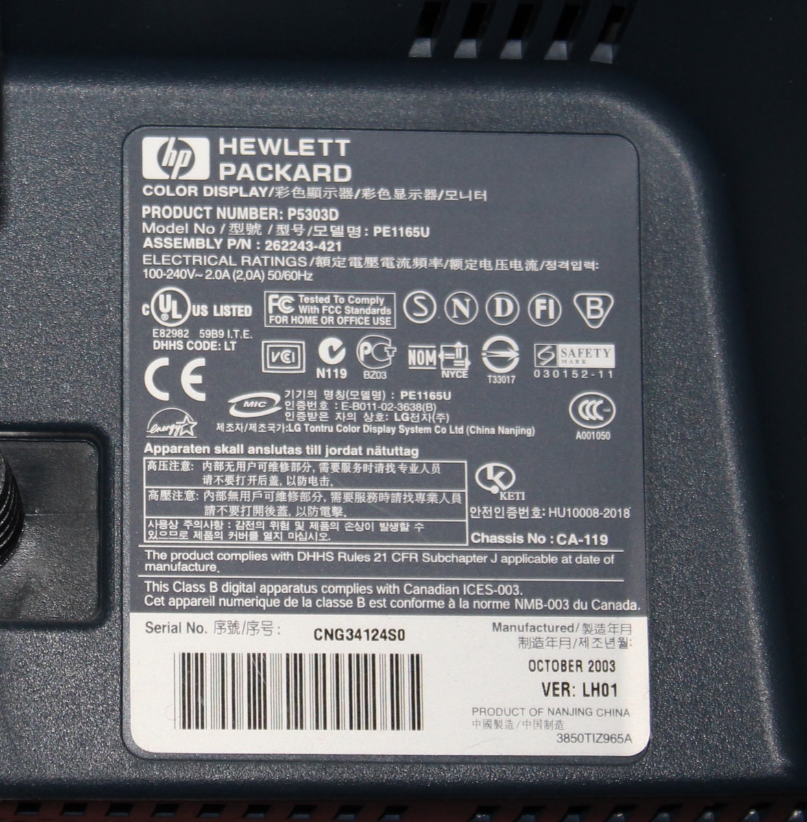 Das Typenschild auf der Rückseite eines HP-Monitors, mit Produktnummer, Modellnummer und Seriennummer zwischen Prüfzeichen und Text in mehreren Sprachen